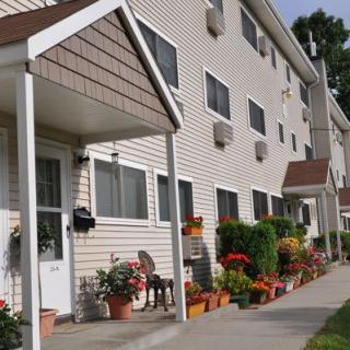 A view of a residential apartment building with well-maintained landscaping and a sidewalk.