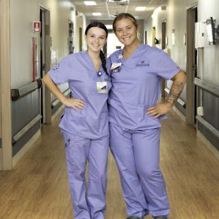 Two nurses pose together in the hospital hallway, showcasing their teamwork and positive spirit.