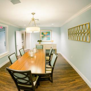 A modern dining room with a wooden table, chairs, and elegant lighting.