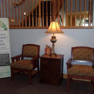 A cozy waiting area featuring comfortable chairs, a decorative lamp, and a small table.