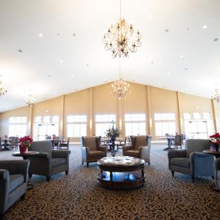 A spacious lounge with elegant chandeliers, comfortable seating, and large windows.