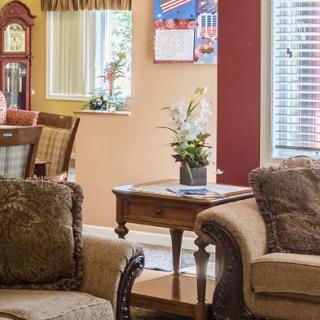 A cozy living room with comfortable sofas, a wooden table adorned with a plant, and a grandfather clock in the background.