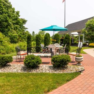 A cozy outdoor patio area surrounded by greenery and featuring a shaded umbrella and seating.