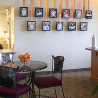 A cozy cafe interior with framed artwork on the wall and a small round table with chairs.