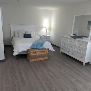 A serene and minimalistic bedroom featuring a cozy bed, a stylish dresser, and ample natural light.