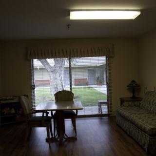 A cozy room interior with a table and chairs next to a large window overlooking a courtyard.
