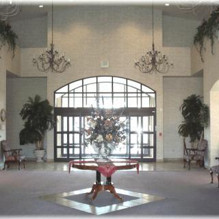 A spacious lobby with chandeliers, decorative plants, and a central table arrangement.