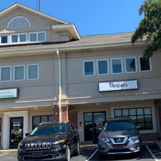 A view of a commercial building featuring office spaces with two parked vehicles in the foreground.