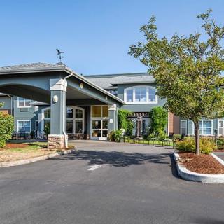 A modern building with a landscaped entrance and driveway.