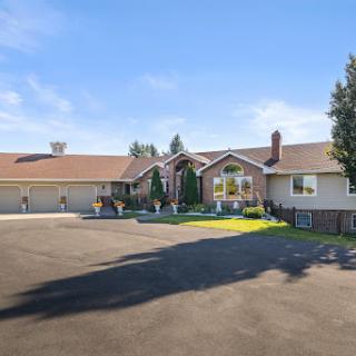 A beautifully landscaped residential home with a spacious driveway under a clear blue sky.