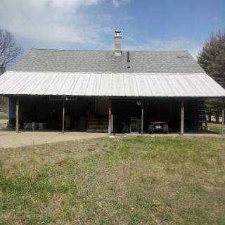 A rural house with a metal roof and covered porch.