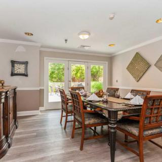 A well-furnished dining room with a wooden table, chairs, and decorative elements by large windows.