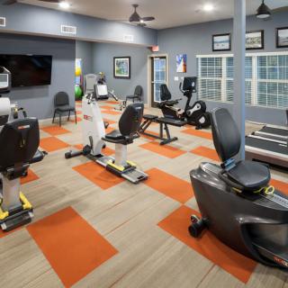 A modern gym with various exercise equipment, including treadmills and stationary bikes.