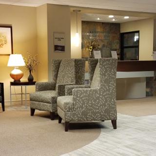 A cozy seating area featuring patterned armchairs, a side table, and a warm lamp.
