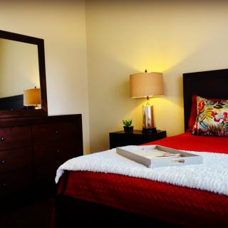 A cozy bedroom with a neatly made bed, featuring warm lighting and stylish decor.