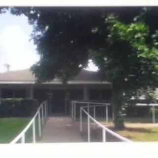 A building with a ramp leading to the entrance, surrounded by trees.