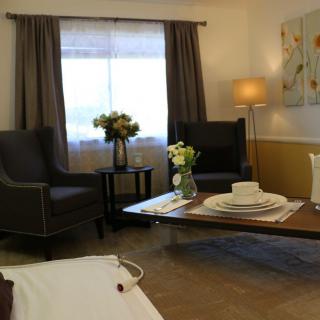 A cozy living room featuring armchairs, a coffee table set with dishes, and floral decorations under soft lighting.
