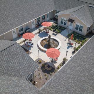 Aerial view of a courtyard with a central fountain surrounded by patio seating and red umbrellas.