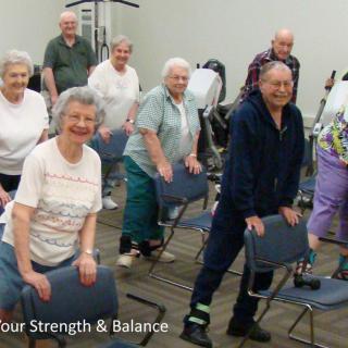 A group of seniors participating in a chair exercise class to improve strength and balance.