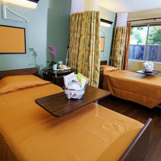 A cozy hotel room featuring two beds with orange bedding and a lovely flower arrangement.