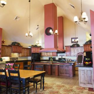 A spacious kitchen with high ceilings and wooden cabinetry, featuring a central island and a dining area.