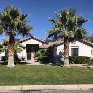 A suburban house with well-maintained landscaping and palm trees under a clear blue sky.
