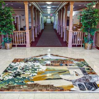 A beautifully decorated hallway featuring a large, colorful rug and potted plants.