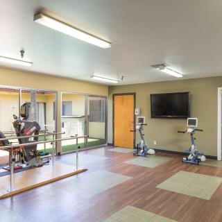 An indoor gym with exercise equipment, including stationary bikes and a television.