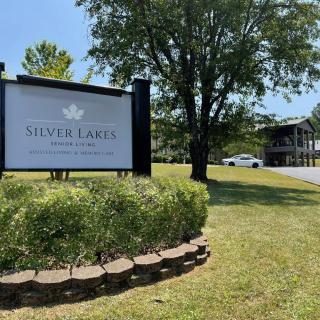 Sign for Silver Lake Apartments near a tree and lawn, with a building in the background.