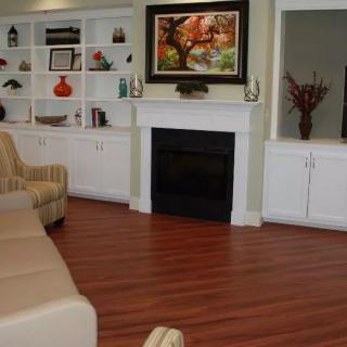 A cozy living room with a fireplace, hardwood floors, and built-in shelves adorned with decorative items.