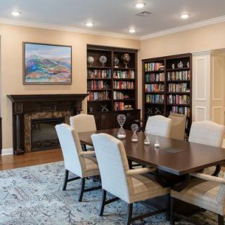 A cozy library dining room with bookshelves, a fireplace, and elegant seating.
