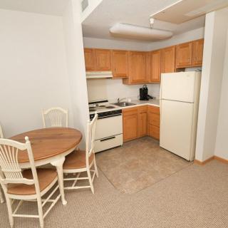 A compact kitchen and dining area with a small round table, chairs, and basic appliances.