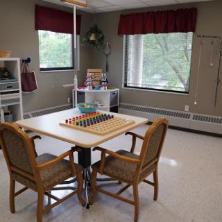 A cozy recreational space featuring a table with colorful toys and comfortable chairs, illuminated by natural light from the windows.