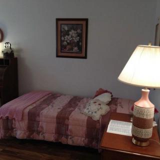 A cozy bedroom with a single bed and a warm lamp on the side table.