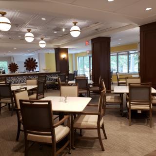 A modern restaurant dining area with neatly arranged tables and chairs under decorative lighting.