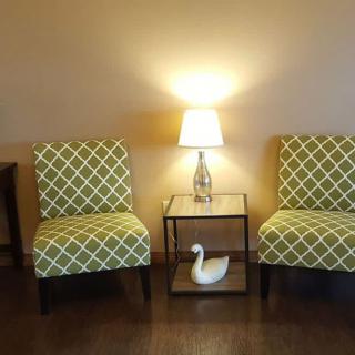 A cozy living room setup with two patterned chairs, a small lamp on a side table, and a decorative swan figurine.