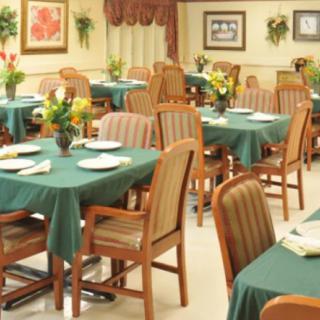 An empty restaurant dining area with green tablecloths and neatly arranged tables and chairs.
