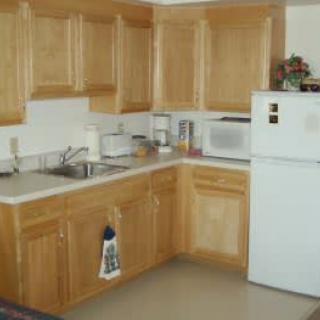 A kitchen with wooden cabinets, a refrigerator, and a microwave.