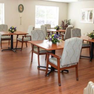 A cozy dining area with wooden floors, neatly arranged tables, and comfortable chairs.
