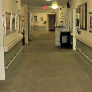 A carpeted hallway with framed artwork on the walls and overhead lighting.