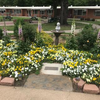 A beautifully landscaped garden with vibrant flowers and a small statue centerpiece.