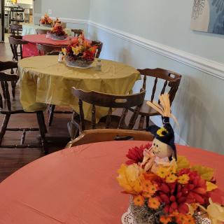 A restaurant dining area with tables decorated in fall-themed centerpieces featuring vibrant autumn colors.