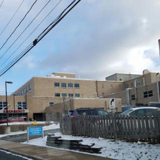 A view of a hospital building alongside a snowy road.