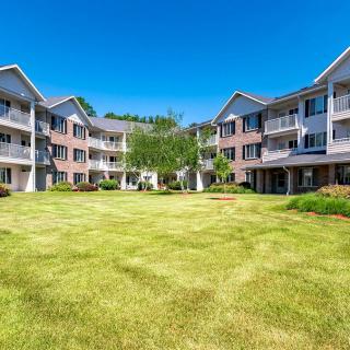 A residential apartment complex with a well-maintained lawn and balconies under a clear blue sky.