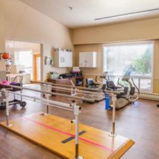 A well-equipped physical therapy and rehabilitation room with exercise equipment and parallel bars.