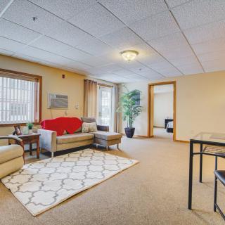 A cozy living room with a sofa and rug, featuring large windows and modern decor.