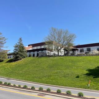 A modern building situated on a grassy hill under a clear blue sky.