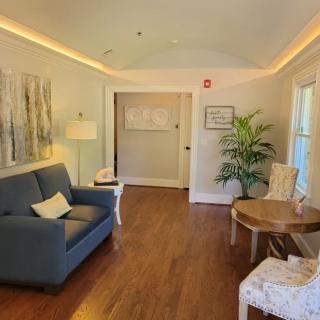 A cozy living room with a blue sofa, armchairs, and an indoor plant, featuring wooden flooring and soft lighting.