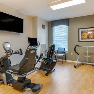 A compact fitness room equipped with stationary bikes and a treadmill.