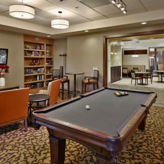 A cozy lounge area featuring a pool table and bookshelves, perfect for relaxation and entertainment.